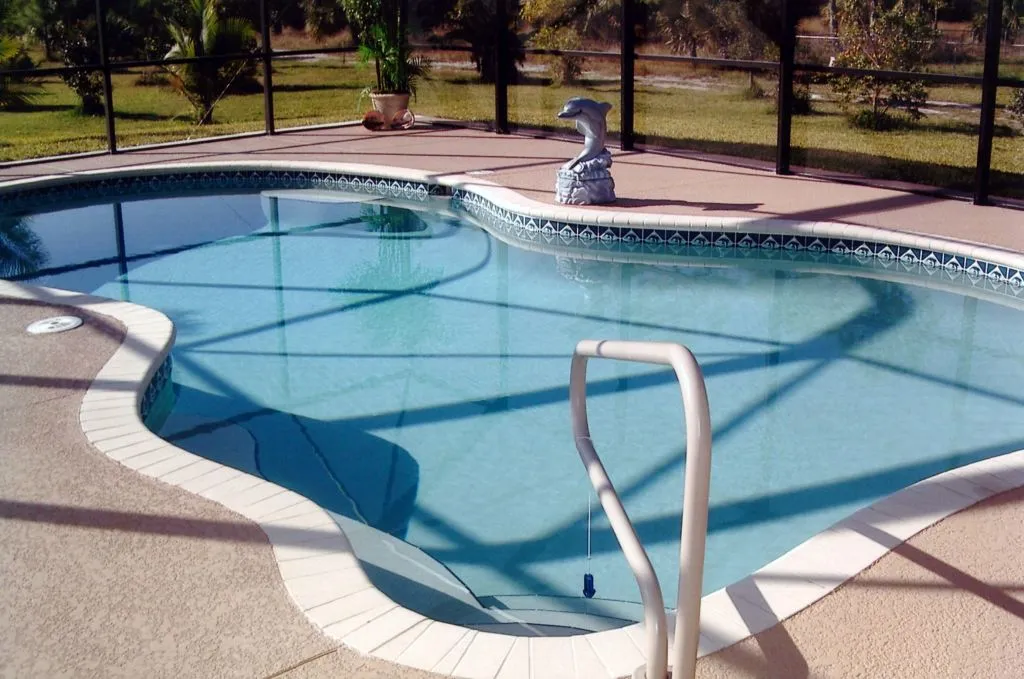 A freeform vinyl-liner pool with a tiled waterline under a screened patio enclosure.
