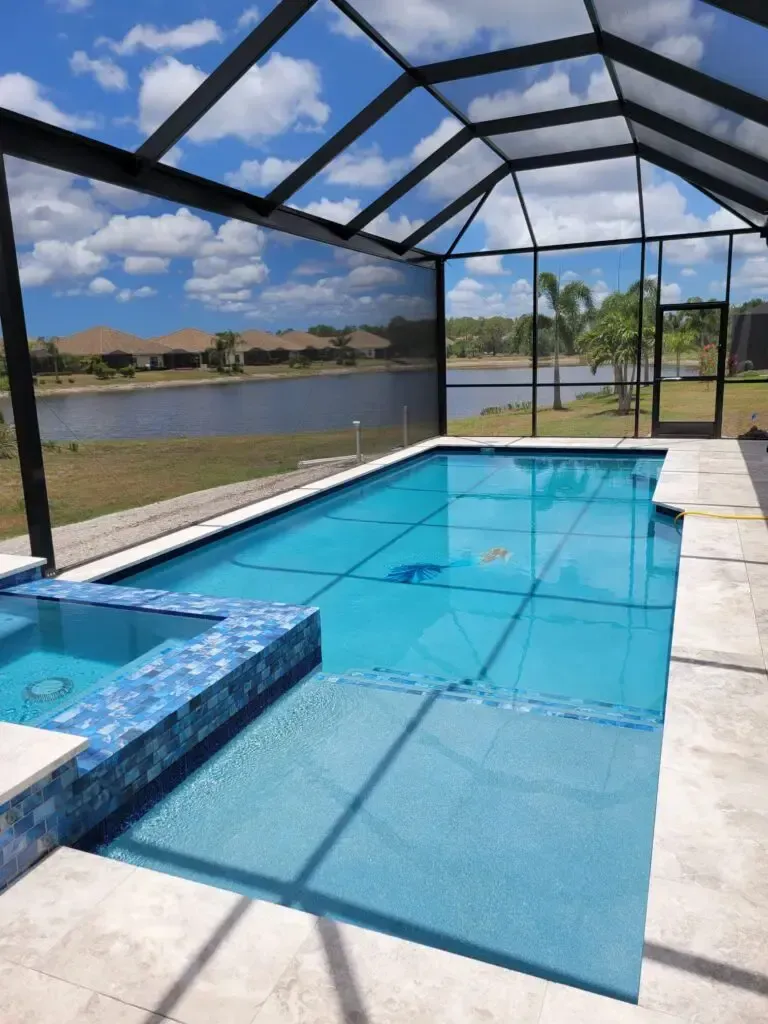 Rectangular pool with a raised tiled spa under a screened lanai overlooking a lake.