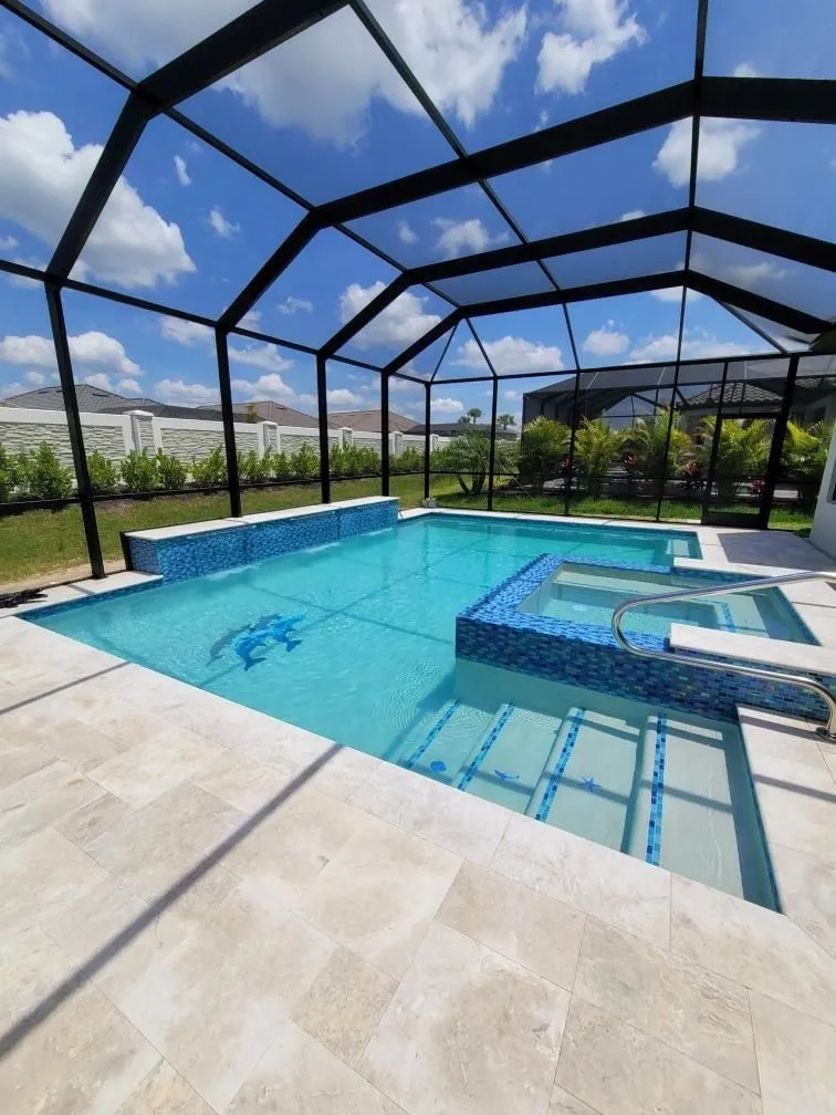 A rectangular pool with a raised blue-tiled spa under a screened enclosure and travertine deck.