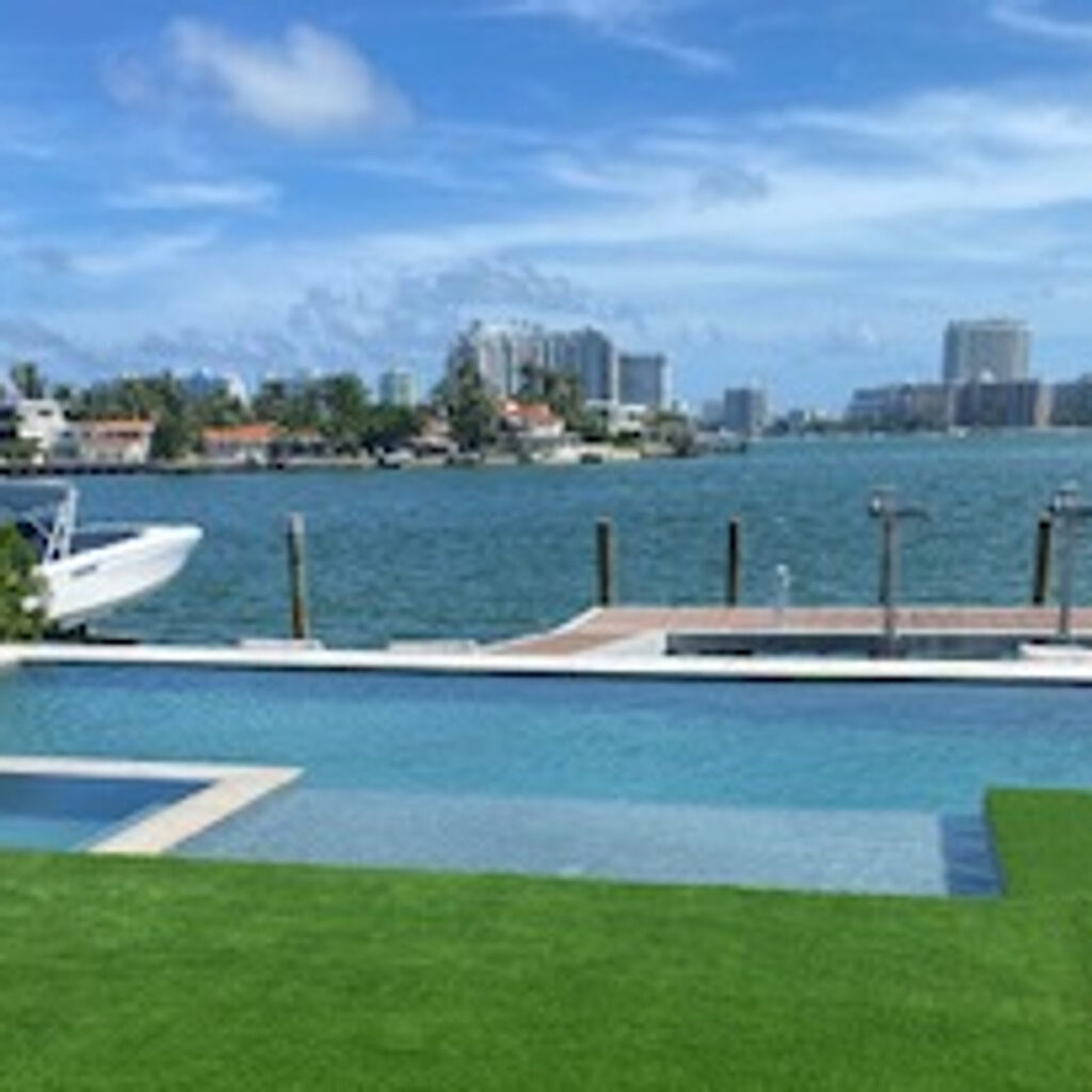Infinity-edge pool overlooking a bay with boats and city skyline in the background.