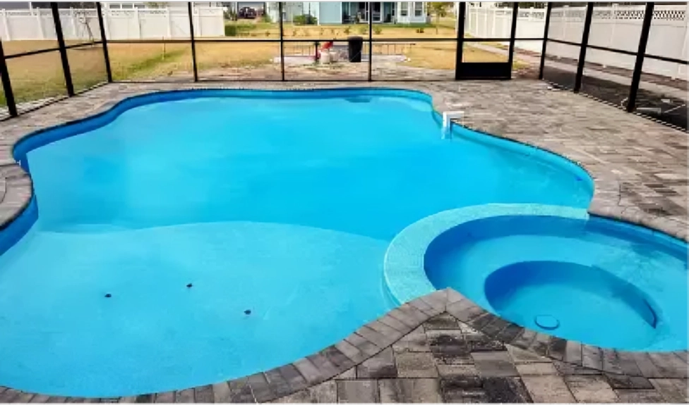 A freeform vinyl-liner pool with an attached round spa under a screened patio enclosure.