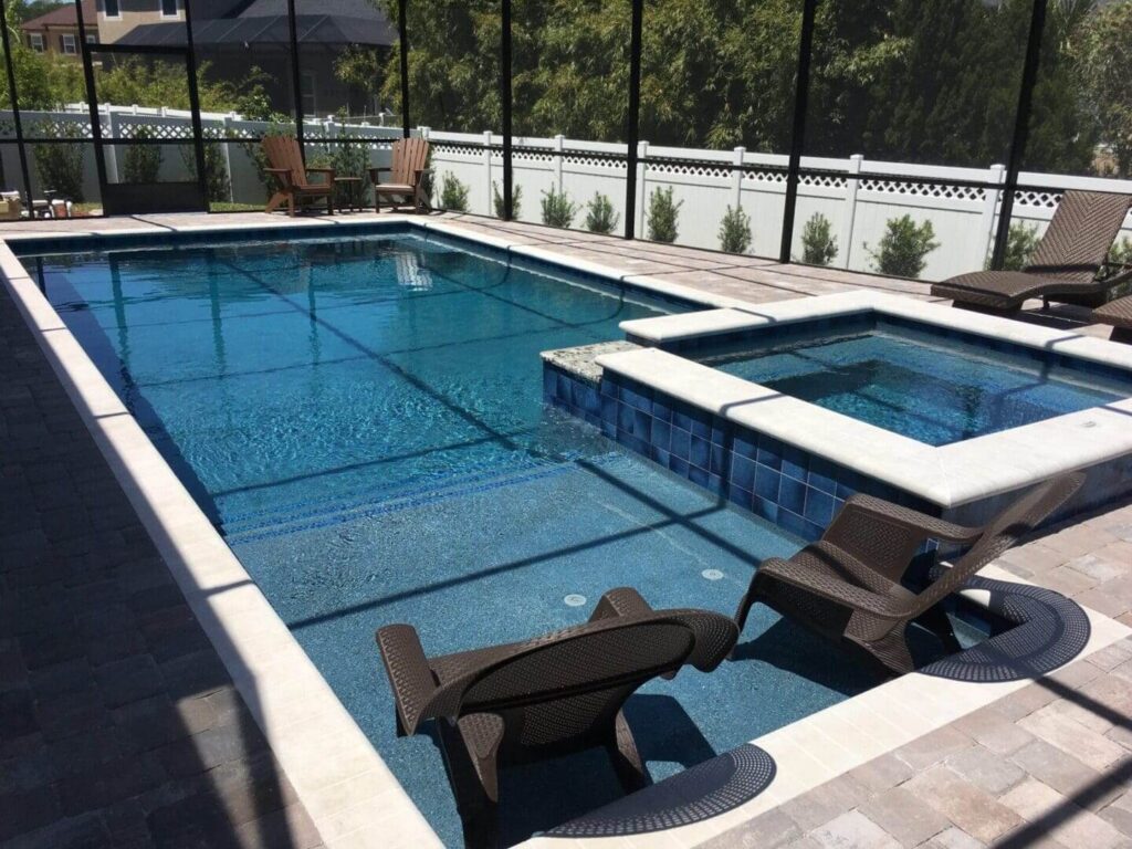 A rectangular pool with in-water loungers and a raised spa under a screened enclosure.