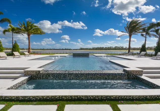 An elevated infinity-edge rectangular pool with a raised spa and water bowls overlooking a lake.