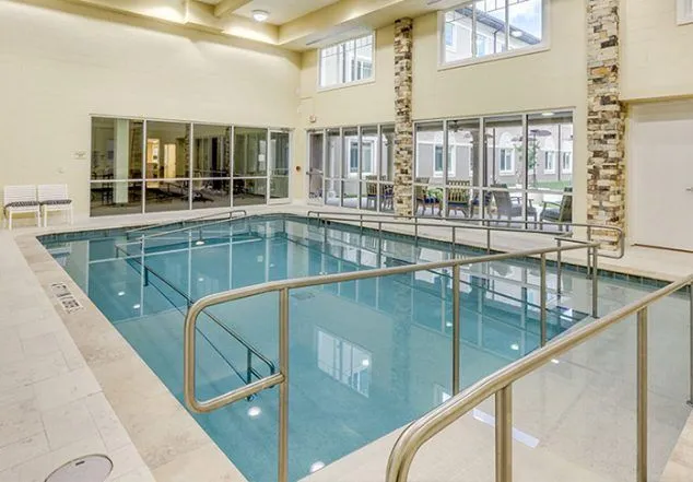 An indoor rectangular lap pool with metal handrails inside a resort or clubhouse facility.