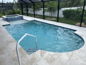 A freeform pool with a raised spa and travertine deck inside a screened lanai.