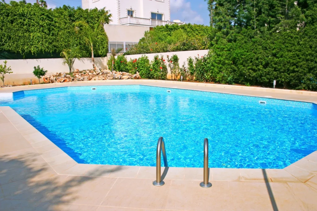 A geometric octagonal pool with clear blue water and stone coping in a landscaped backyard.