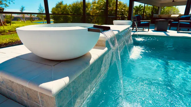 A white water bowl spills into a pool under a screened patio enclosure.