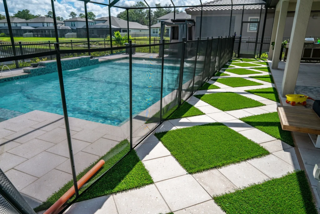 A rectangular pool with tanning ledge inside a screened enclosure, bordered by a checkerboard patio of pavers and turf.