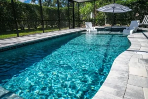 A rectangular pool with two in-water lounge chairs and an integrated spa under a screened patio enclosure.