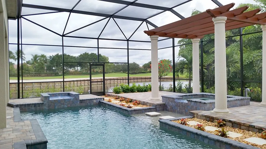 A screened freeform pool with a raised spa and stone planters overlooks a golf course under a pergola-topped lanai.