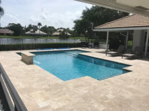 An L-shaped pool with a raised wall water feature overlooks a lake behind the home.