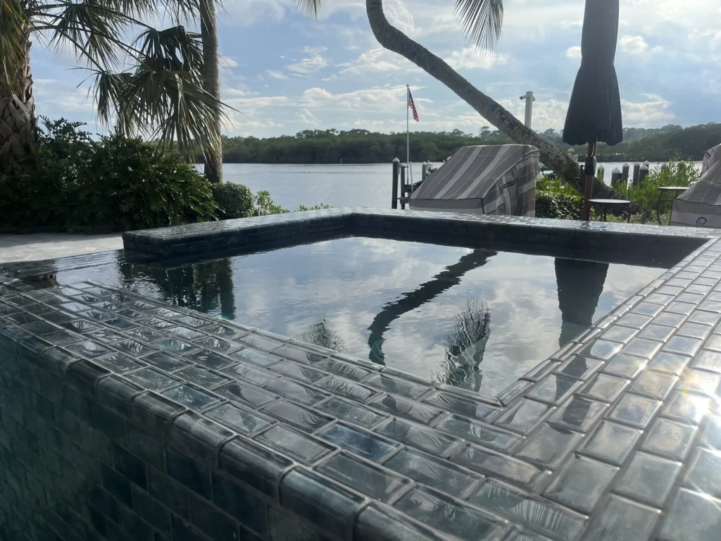 Close-up of a raised all-tile pool edge overlooking a waterway lined with mangroves.