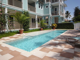 A small rectangular pool along a paved courtyard beside a multi-story condo building.