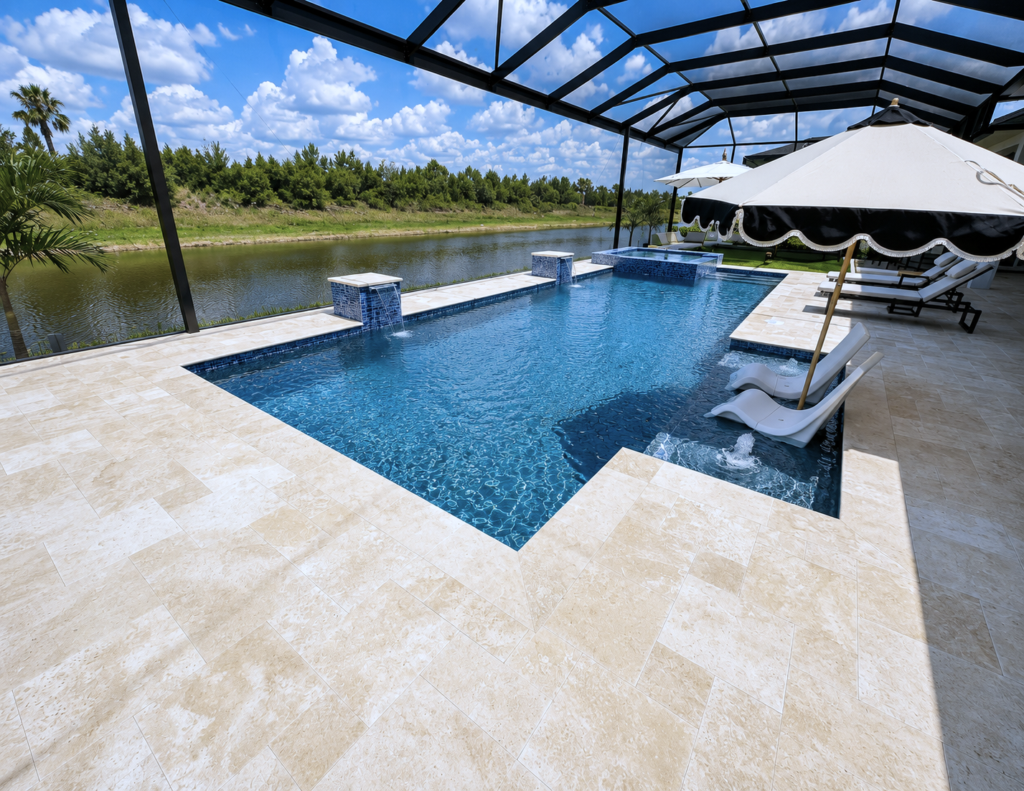 A rectangular pool with raised spa and water bowls sits on a travertine patio beside a canal under a screened enclosure.