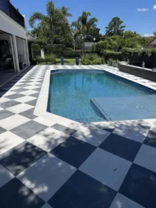 A geometric octagonal pool with a bold black-and-white checkerboard tile deck and a raised sun step with a bubbler jet.