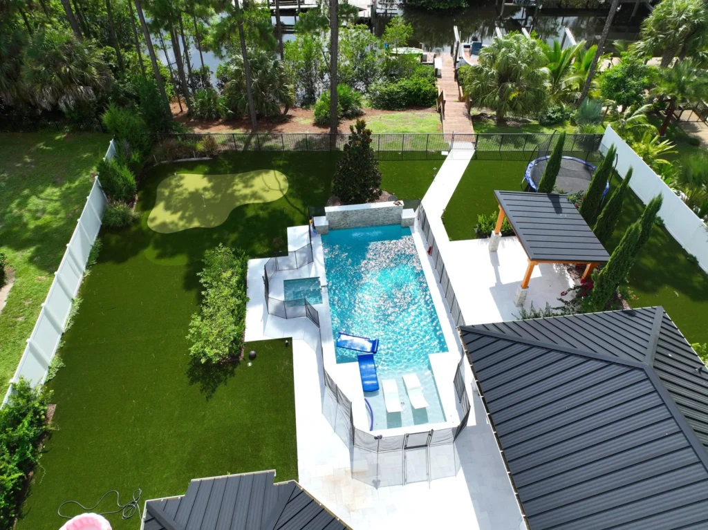 Aerial view of a multilevel backyard pool with raised spa and water feature near a canal.