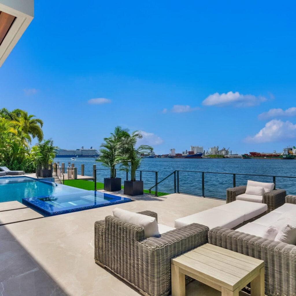 An infinity-edge pool and raised spa overlook a busy waterway with cargo ships and a cruise liner in the distance.