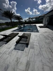 A rectangular pool with an integrated raised-edge spa and water bowls on a stone-paved patio overlooking a canal.