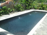 A small rectangular pool with dark water and stone decking surrounded by lush greenery.