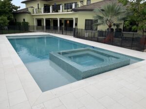 A large rectangular backyard pool with a raised tiled spa in front of a two-story house.