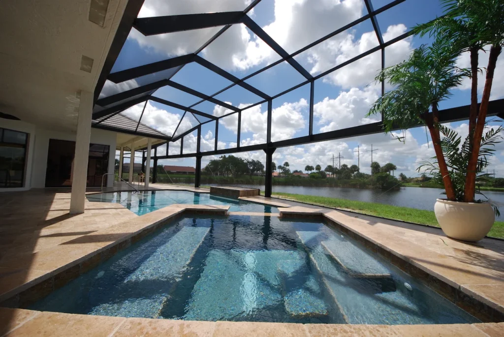 A screened pool enclosure with tiered tanning steps in the foreground and a lake view beyond.