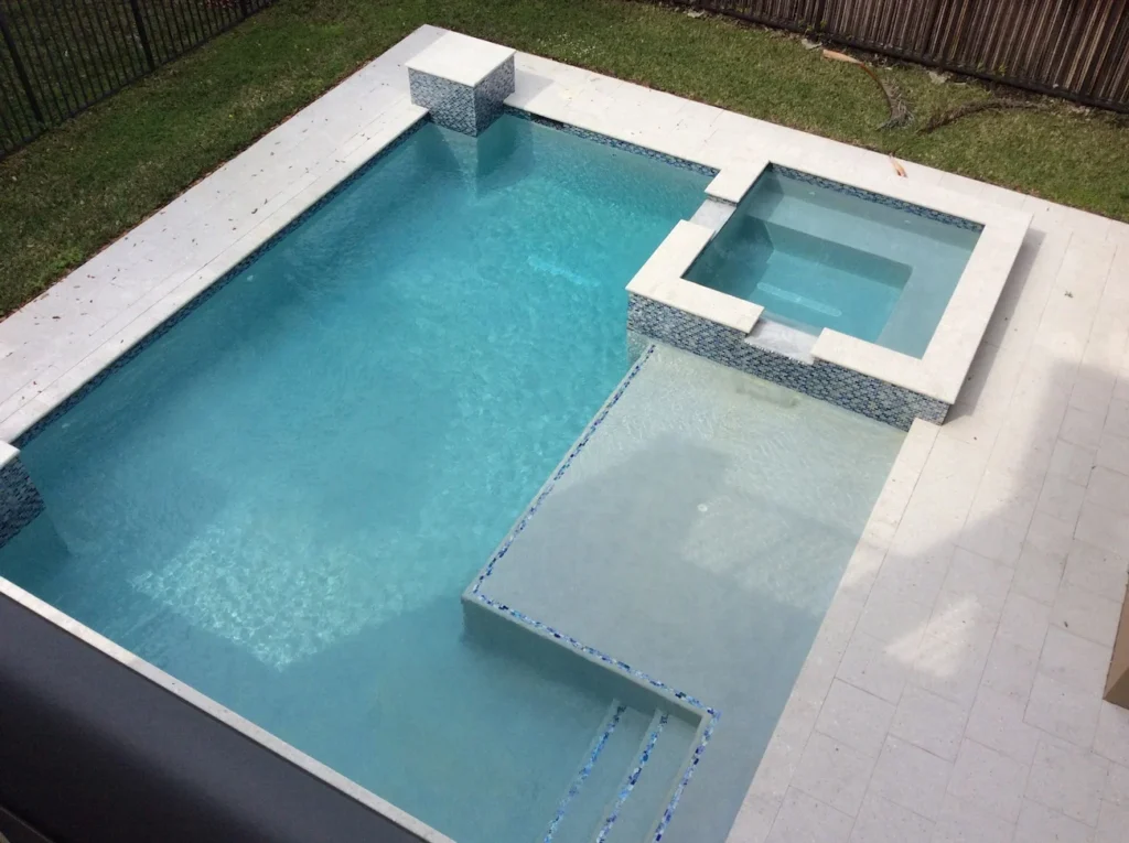 Overhead view of a rectangular pool with a raised spa, tanning ledge, and glass tile accents.