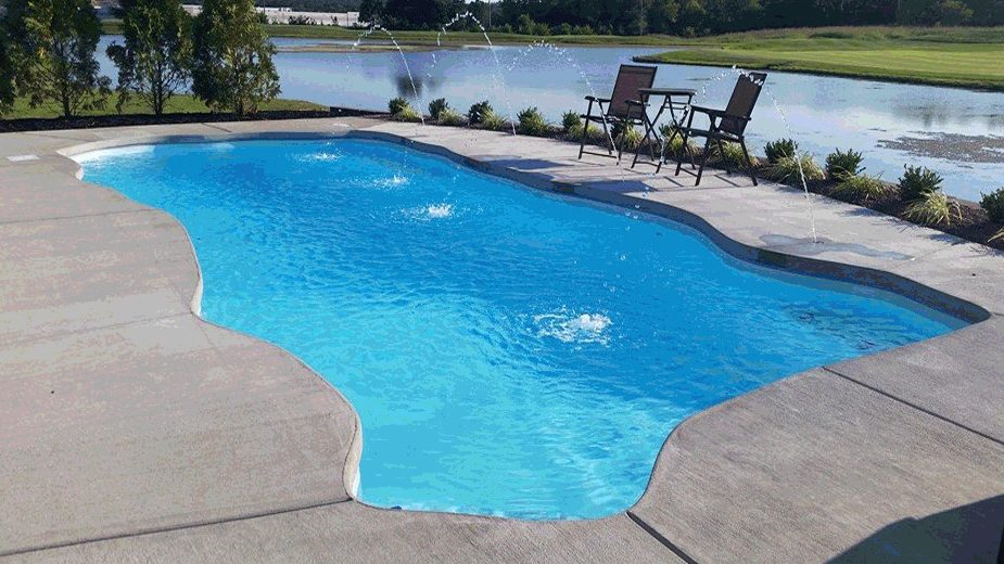 Freeform fiberglass pool with deck jets beside a pond and golf course.
