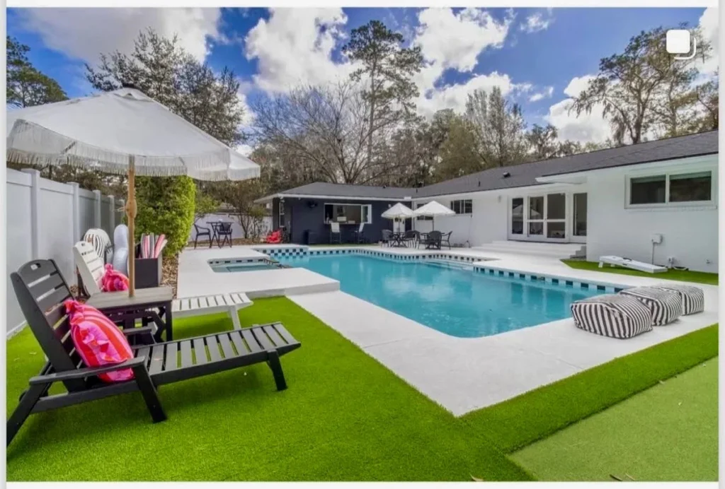 A rectangular backyard pool with an attached raised spa, surrounded by turf, a concrete patio, and lounge furniture under an open sky.