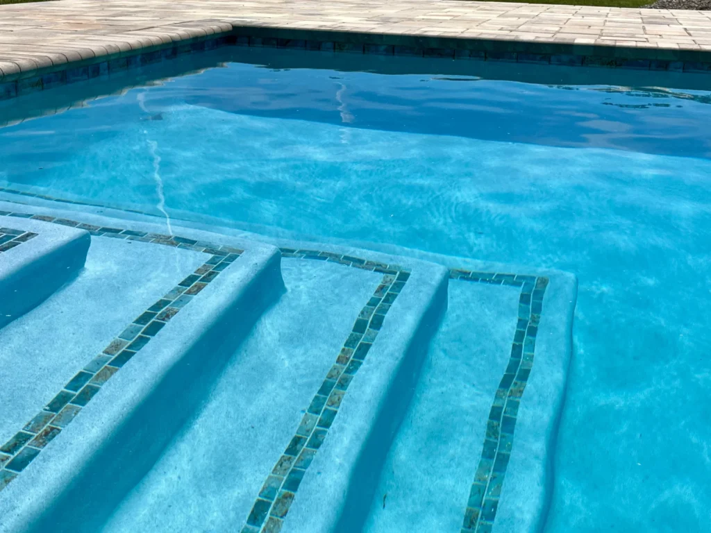 Close-up of wide tiled entry steps leading into a rectangular pool with blue water.