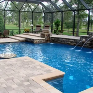 A screened pool with a raised stone wall waterfall, deck jets, and a golf course view beyond the enclosure.