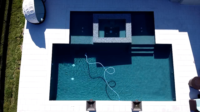 Aerial view of a rectangular pool with a raised square spa and dark plaster finish, seen from directly above.