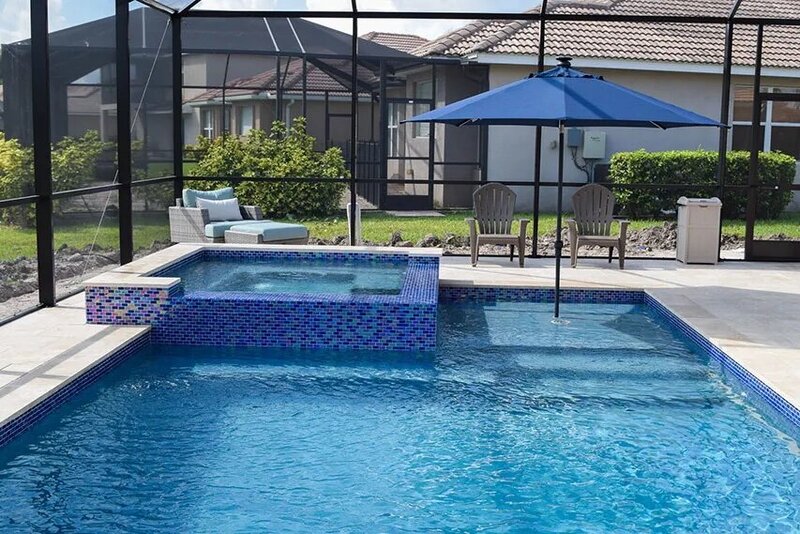 A small rectangular pool with a tiled raised spa and sun shelf under a screened lanai.