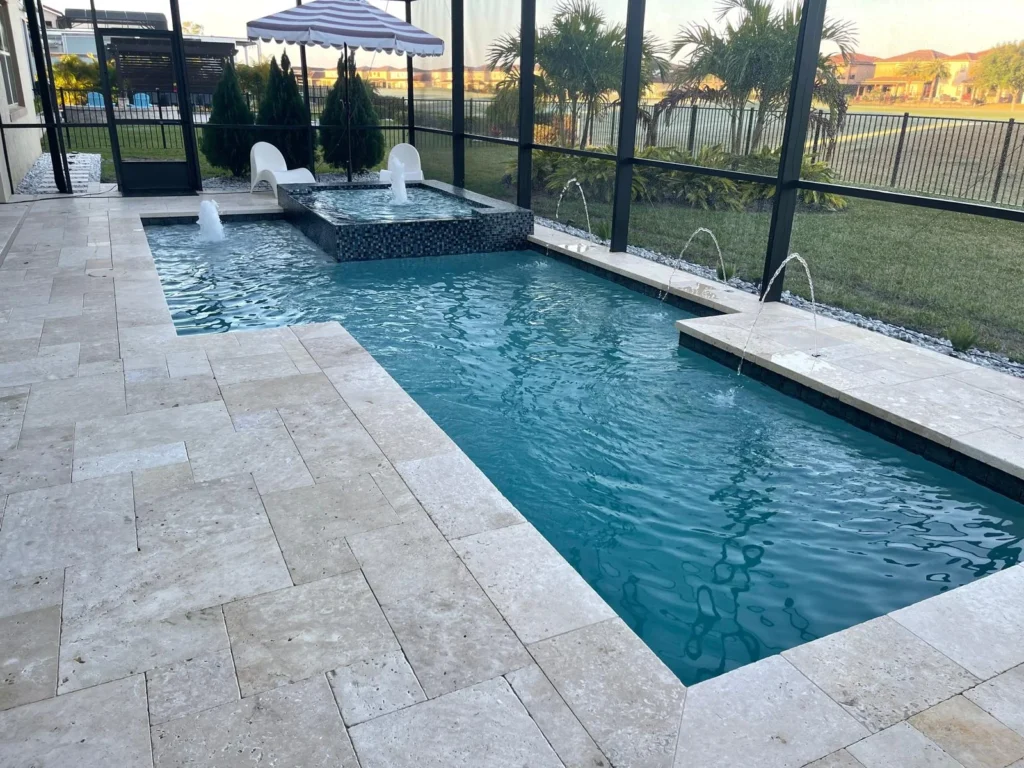 An L-shaped pool with a raised spa and deck jets under a screened lanai at dusk.