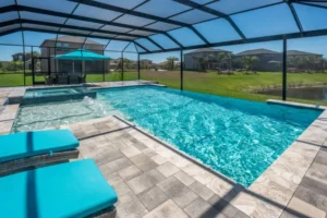 A rectangular pool with a raised spa and bubbler jets under a screened enclosure overlooking a pond.