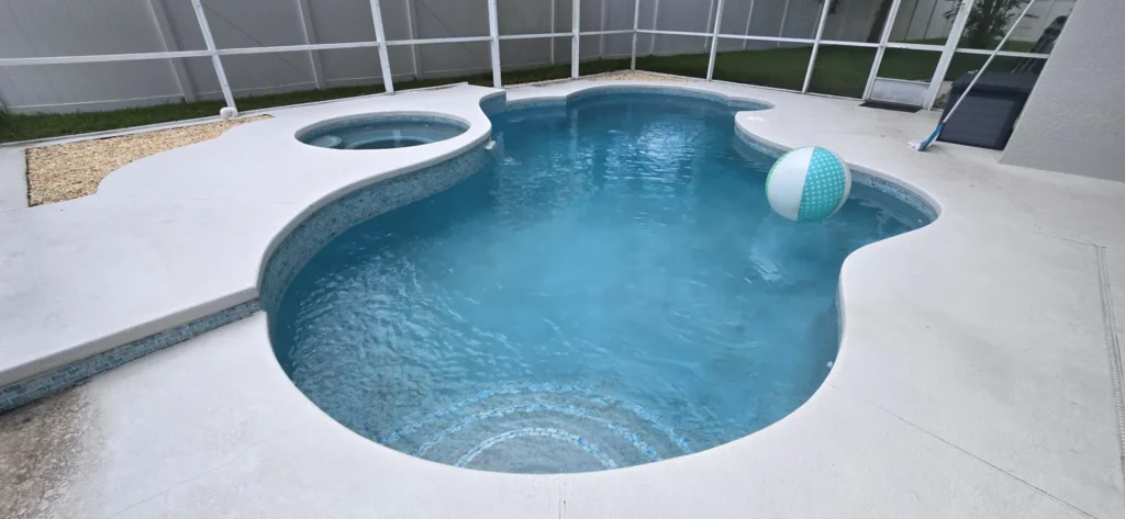 A freeform vinyl-liner pool with an adjacent round spa under a screened patio enclosure.