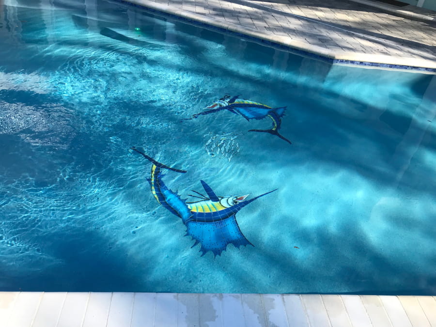 Close-up of detailed sailfish mosaic tiles set into a pool floor.