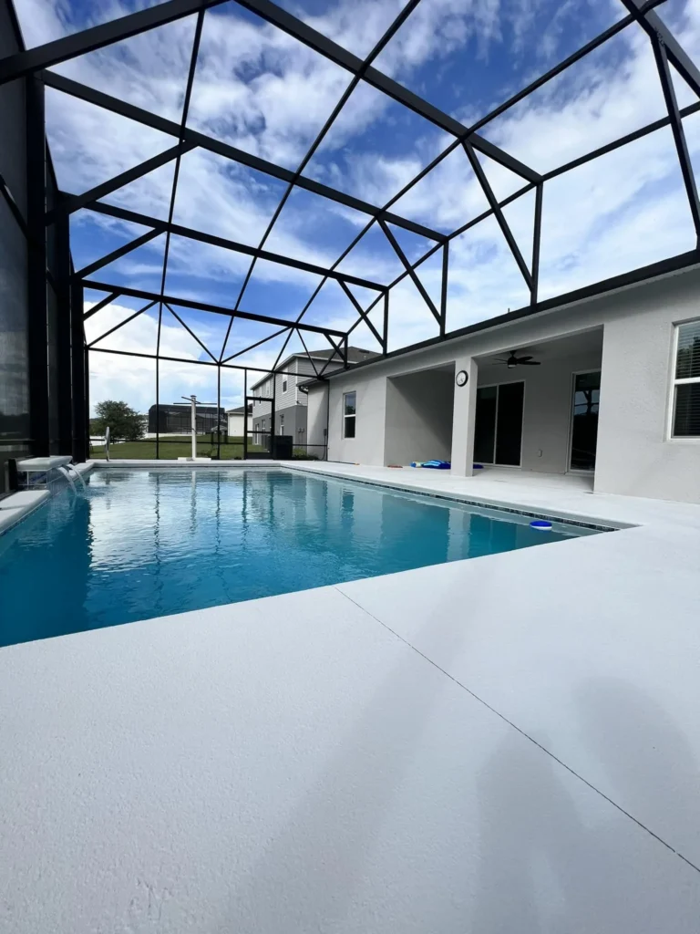 A screened-in rectangular pool with a small water scupper feature beside a new home.