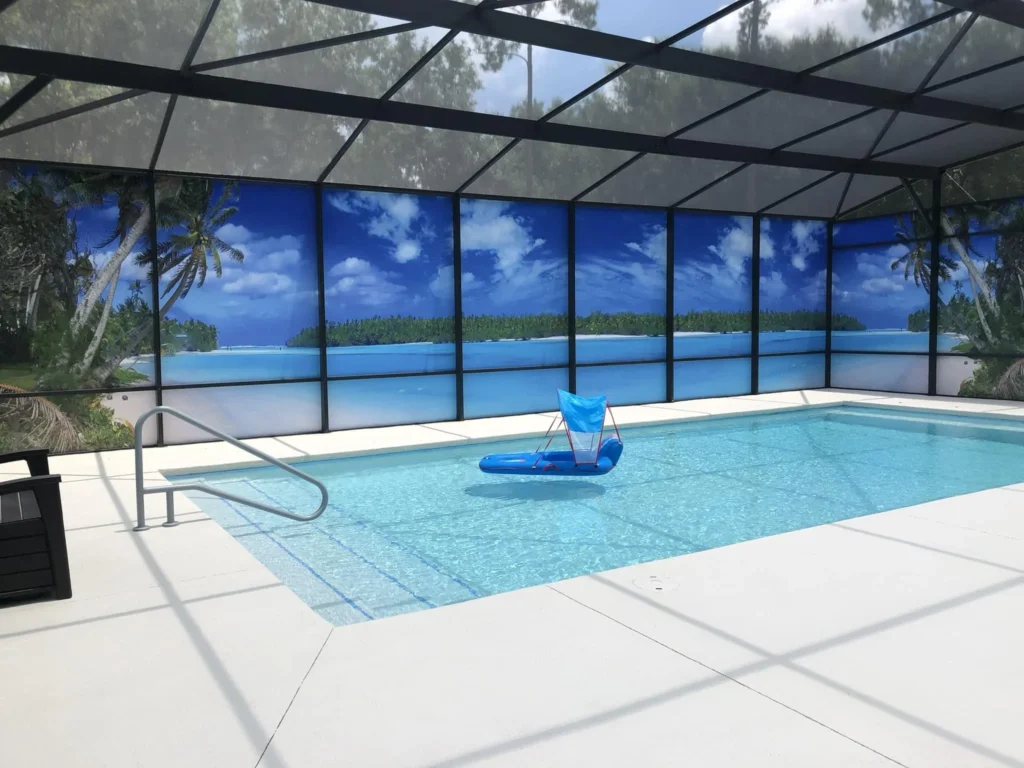 A small rectangular screened pool with a floating lounger and printed tropical scenic screen panels.