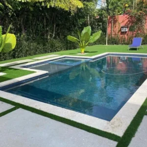 A rectangular backyard pool with an attached spa at one end, surrounded by turf and concrete pavers.