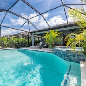 Screened backyard pool with a raised blue-tiled spa and freeform turquoise water under a birdcage enclosure.