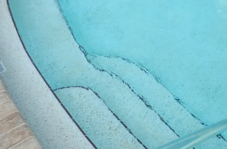 Close-up of curved pool steps and entry corner with light plaster finish.